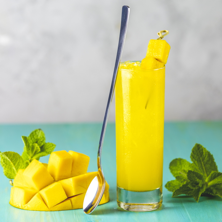 Mango cocktail in high ball glass w/ sectioned mango and spoon
