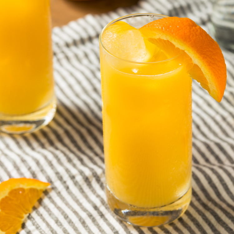Tall glass of orange cocktail w/ fruit wedge garnish